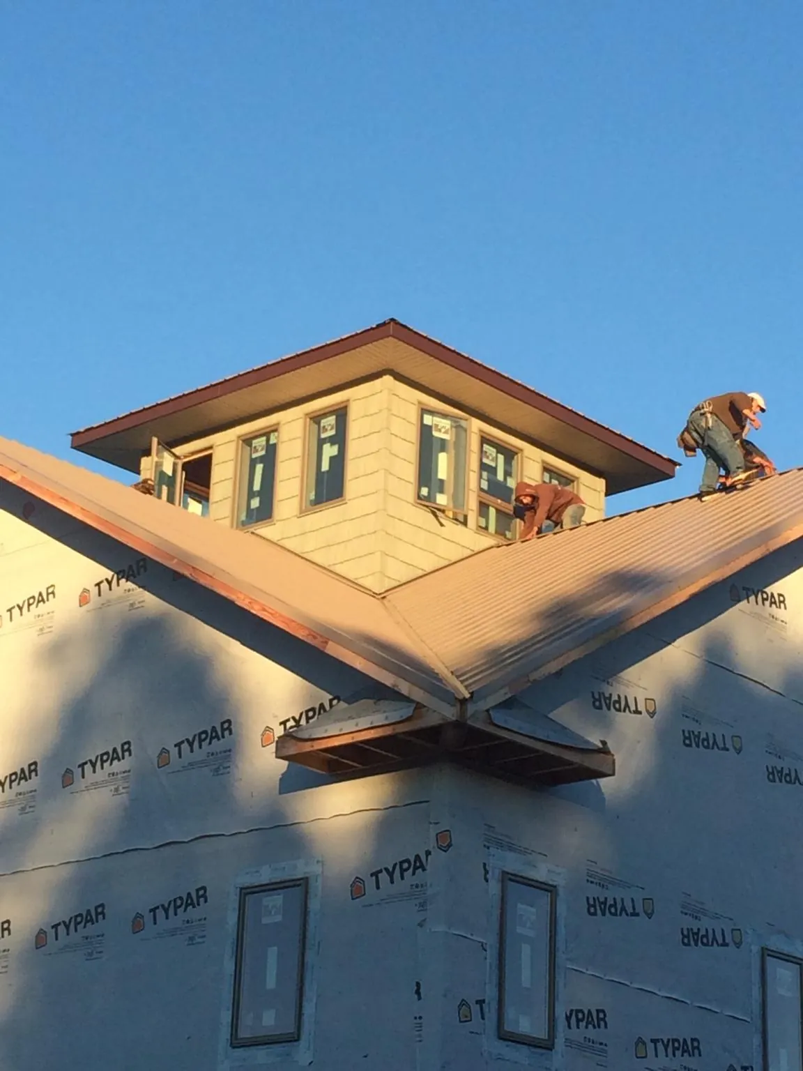 Roofers working around a rooftop cupola on a new metal roof at sunset — Roof Waterproofing in Live Oak by Roofing Brothers